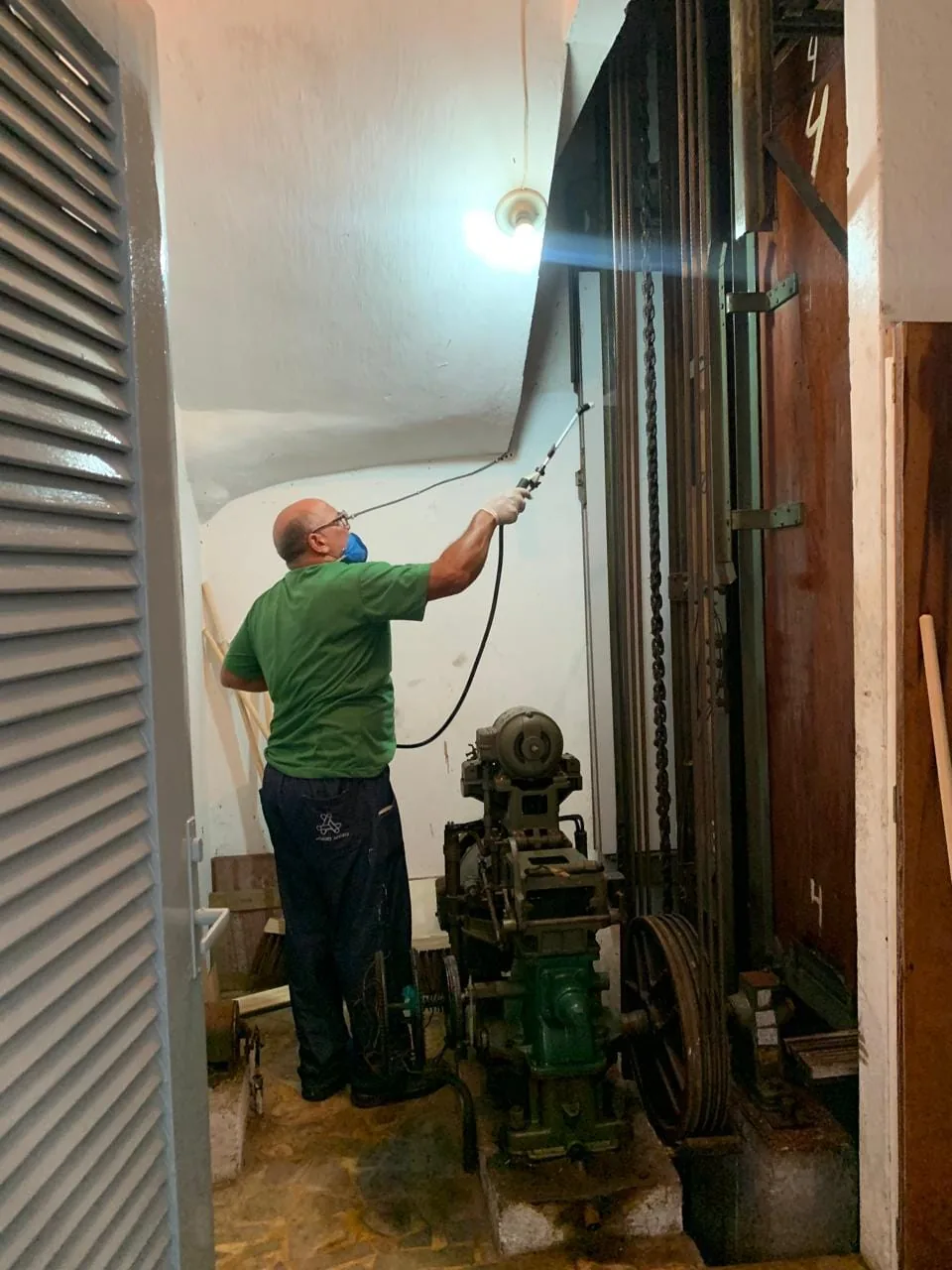 Profissional realizando controle de pragas em área técnica de edifício